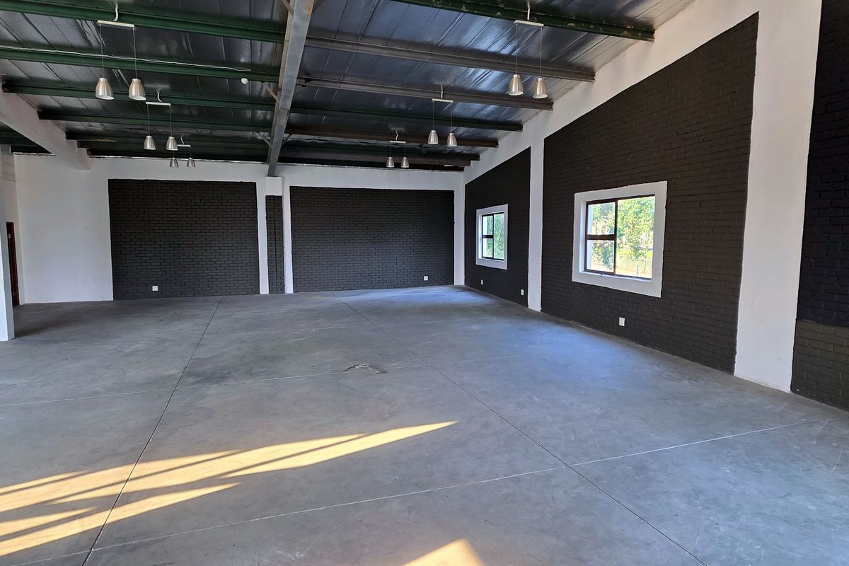 Spacious open-plan industrial unit featuring polished concrete floors, exposed steel roof structure, and modern dark-painted brick feature walls with ample natural light.