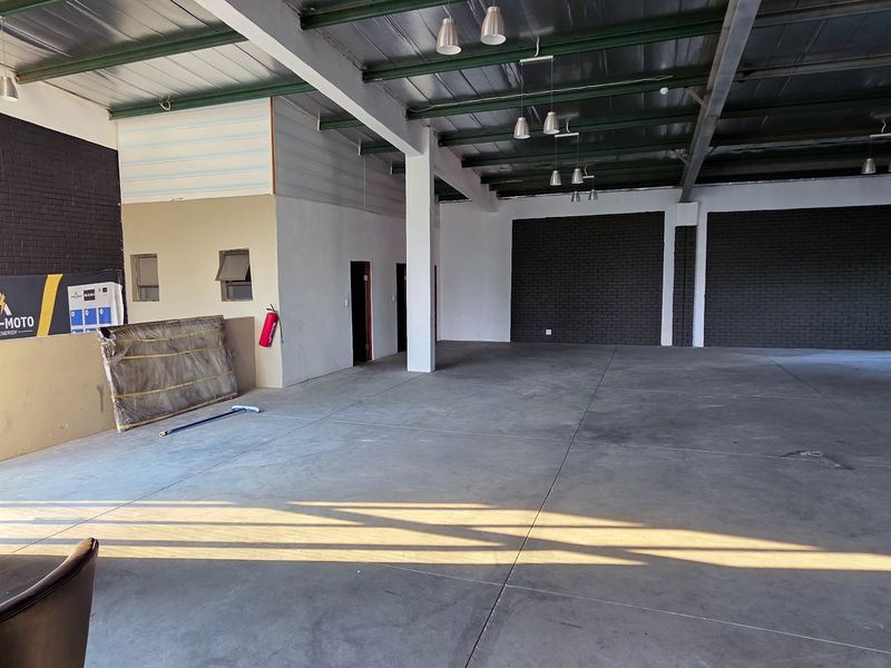 Spacious industrial utility area featuring exposed steel roof trusses, polished concrete flooring, and dark brick accent walls, suitable for various commercial or storage applications.