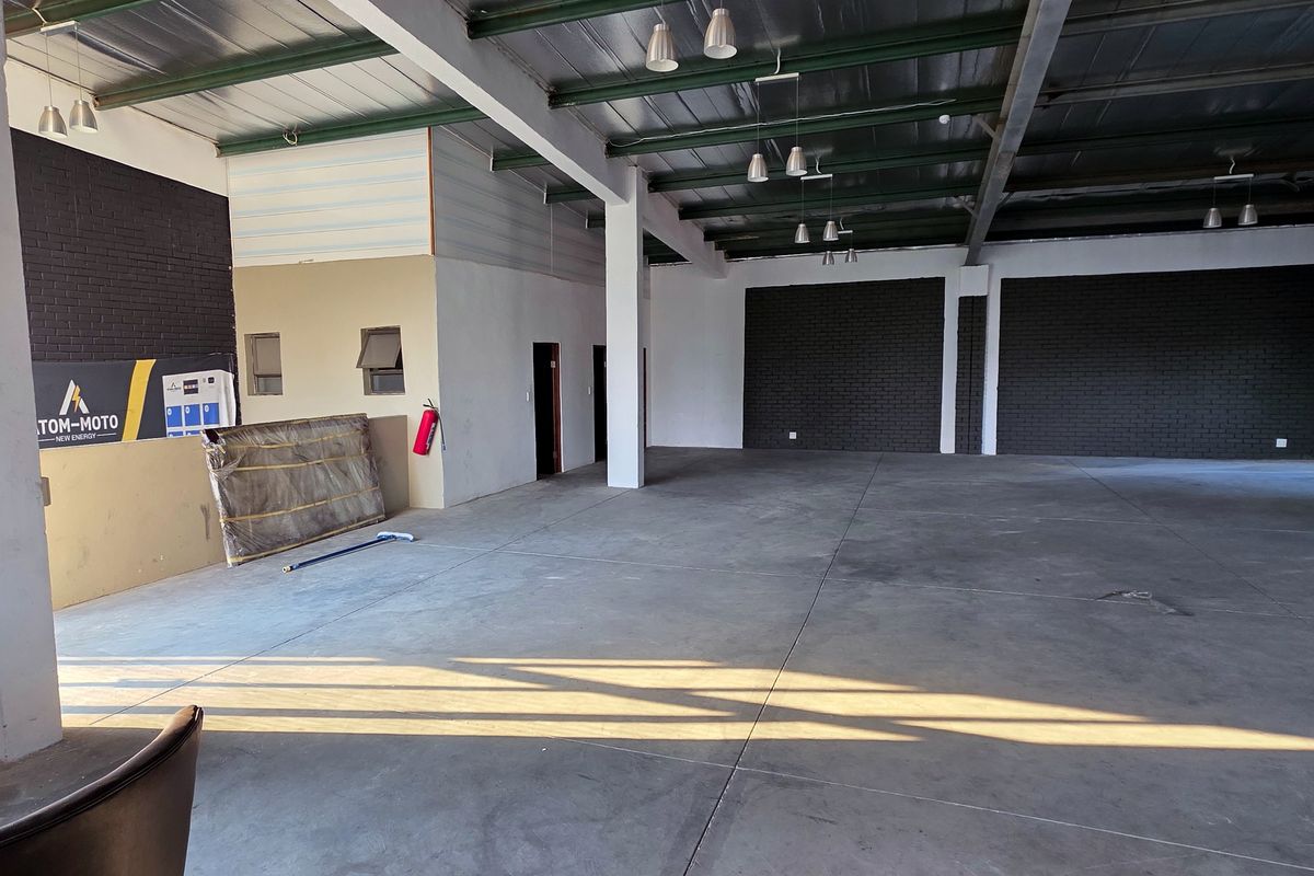 Spacious industrial utility area featuring exposed steel roof trusses, polished concrete flooring, and dark brick accent walls, suitable for various commercial or storage applications.