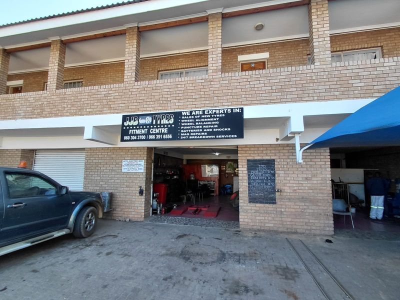 Exterior view of a commercial fitment centre featuring brick facade, roller shutter doors, and dedicated service bays for vehicle maintenance.