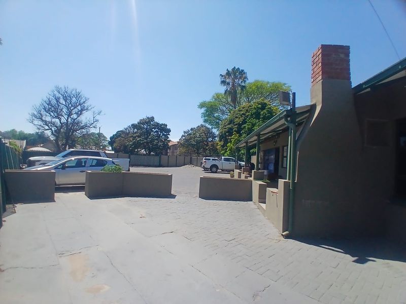 Exterior view of a commercial property featuring a paved driveway, masonry boundary walls, and a prominent brick chimney.