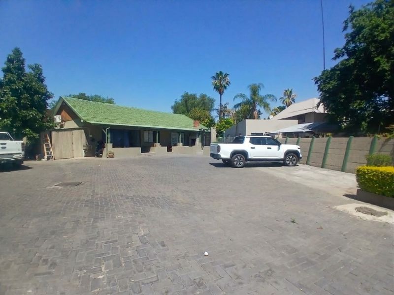 Front exterior view of the commercial property featuring a paved driveway, concrete boundary wall, and a pitched roof structure.