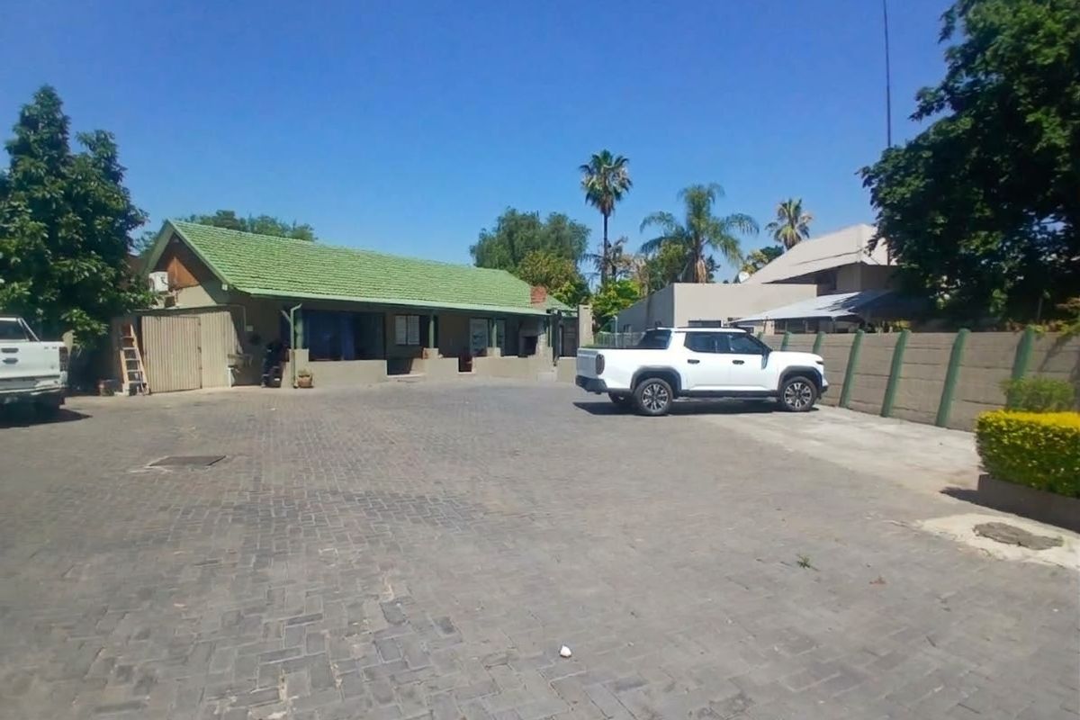Front exterior view of the commercial property featuring a paved driveway, concrete boundary wall, and a pitched roof structure.