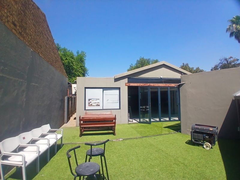 Rear courtyard area featuring artificial turf, boundary walls, and aluminium stacker doors providing access to the interior space.