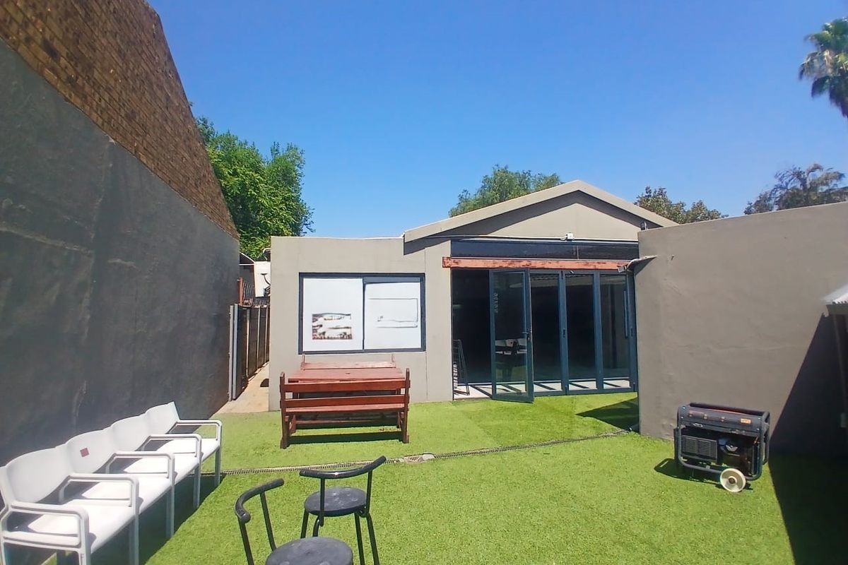 Rear courtyard area featuring artificial turf, boundary walls, and aluminium stacker doors providing access to the interior space.