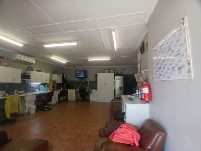 A functional commercial office space featuring built-in cabinetry, tiled flooring, and overhead fluorescent lighting, suitable for a variety of professional business operations.