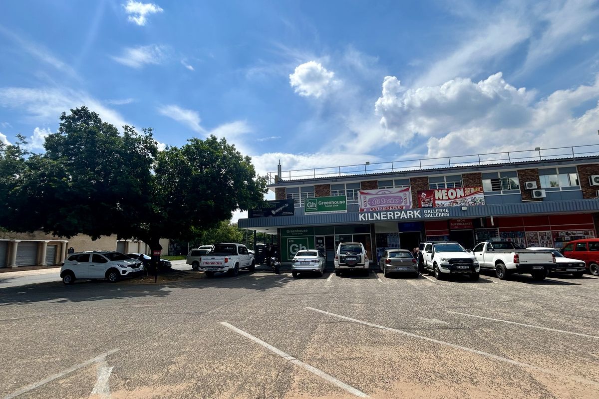 Front exterior view of Kilnerpark Galleries retail center featuring a paved parking area and multiple commercial storefronts with signage.