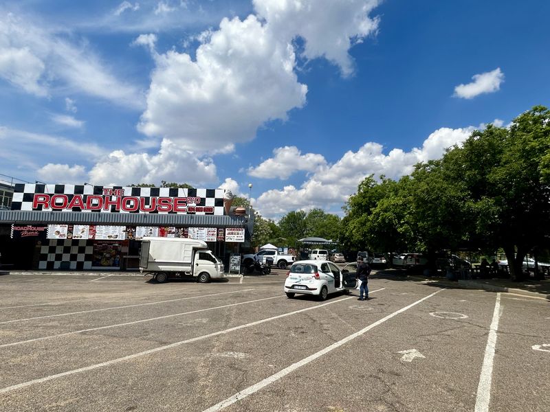 Exterior view of a commercial retail roadhouse property featuring a large asphalt parking area and prominent building signage.