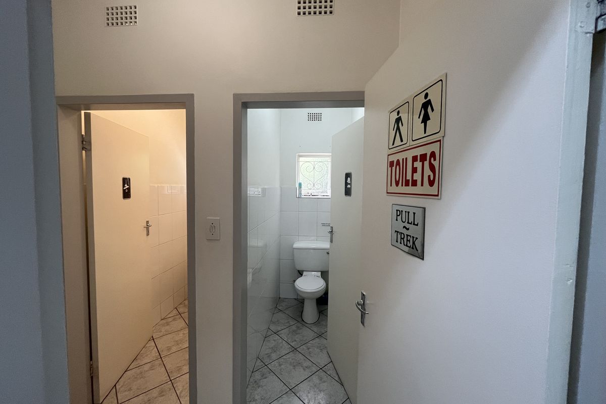 Commercial restroom facility featuring tiled flooring, wall tiling, and functional toilet fixtures with clear signage.