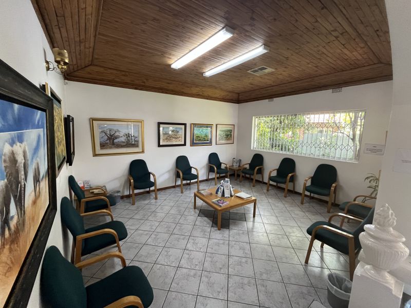 A waiting area or reception room featuring a timber-clad ceiling, ceramic tiled flooring, and security-barred windows, providing a functional commercial space.