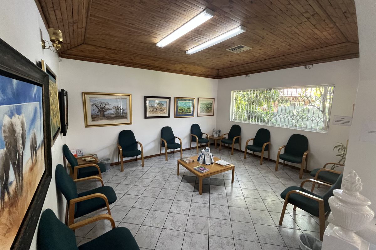 A waiting area or reception room featuring a timber-clad ceiling, ceramic tiled flooring, and security-barred windows, providing a functional commercial space.