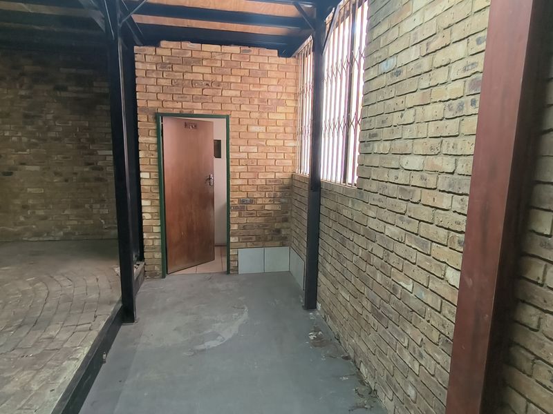 An industrial utility space featuring exposed brick walls, steel structural beams, and concrete flooring, providing a functional area for storage or workshop use.