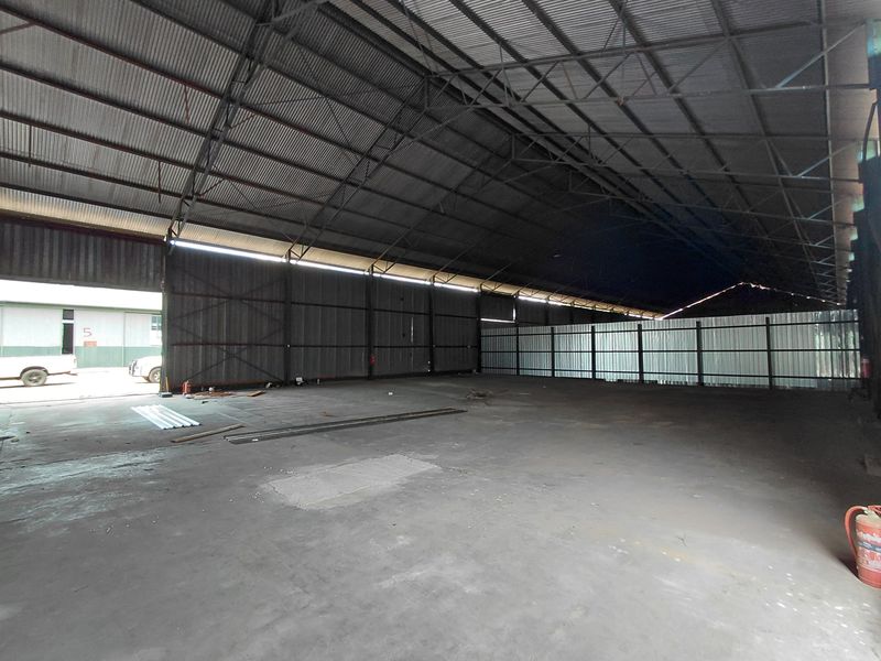 Spacious industrial warehouse featuring high-clearance corrugated metal roofing, steel truss framework, and durable concrete flooring with large access points.