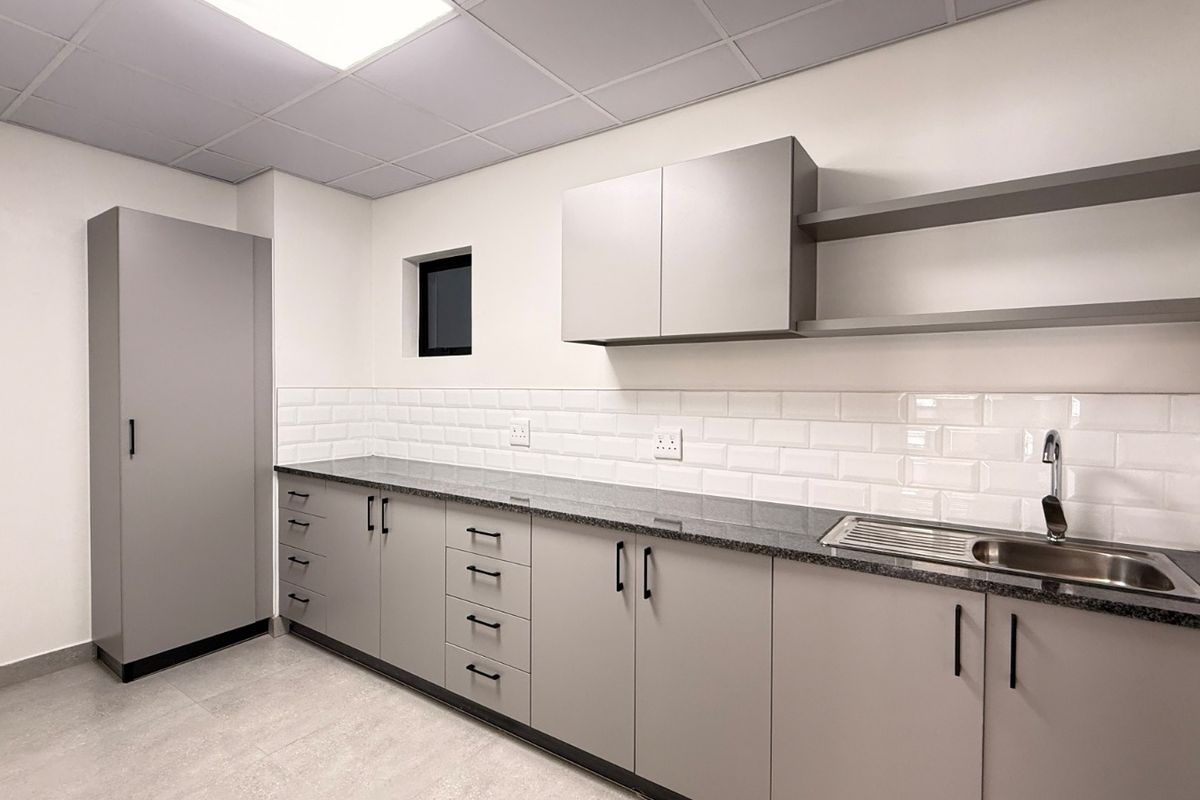 Modern industrial kitchen featuring sleek grey cabinetry, granite countertops, subway tile backsplash, and integrated stainless steel sink with ample storage space.