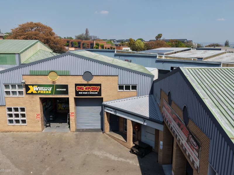 Aerial view of an industrial complex featuring multiple units with corrugated metal roofs, face brick facades, and roller shutter access doors.