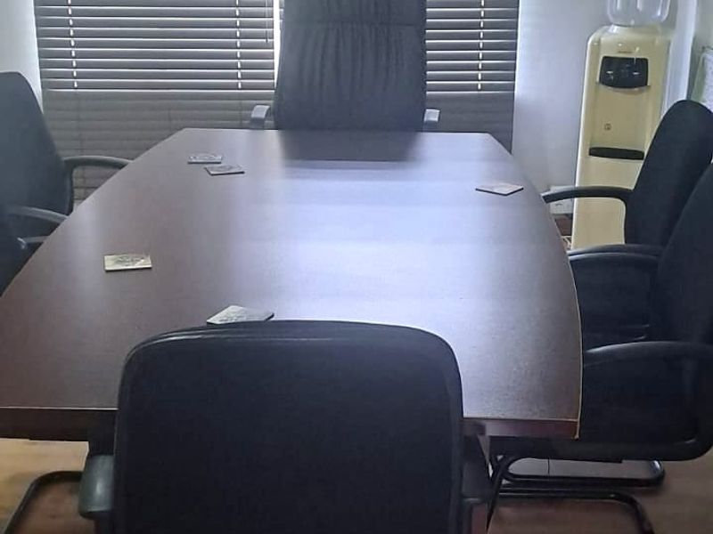 A functional office space featuring wood-look flooring, horizontal window blinds, and a ceiling fan.