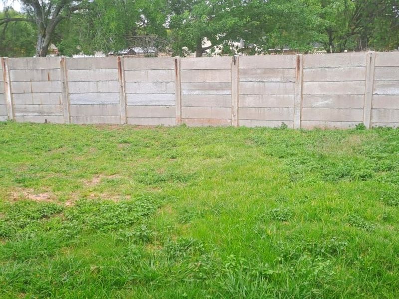 A private outdoor garden area enclosed by a precast concrete boundary wall, featuring a grass lawn.