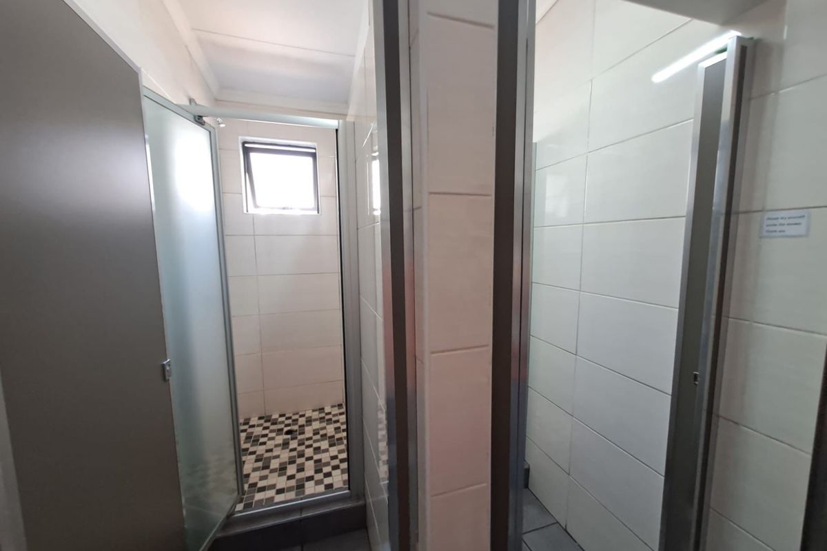 A functional commercial bathroom facility featuring multiple shower cubicles with tiled walls and mosaic floor detailing.