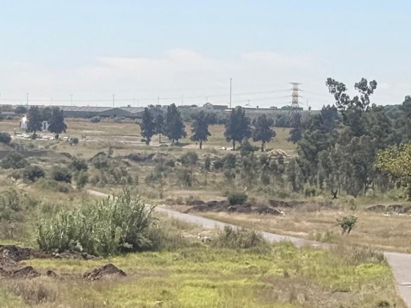 An expansive view of the surrounding industrial landscape, featuring open land, access roads, and distant utility infrastructure.