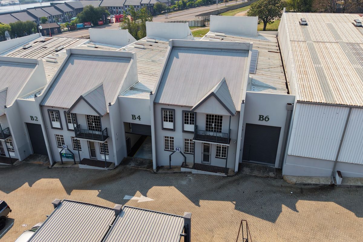 Aerial view of an industrial complex featuring multiple units with corrugated metal roofing, roller shutter doors, and paved access areas.