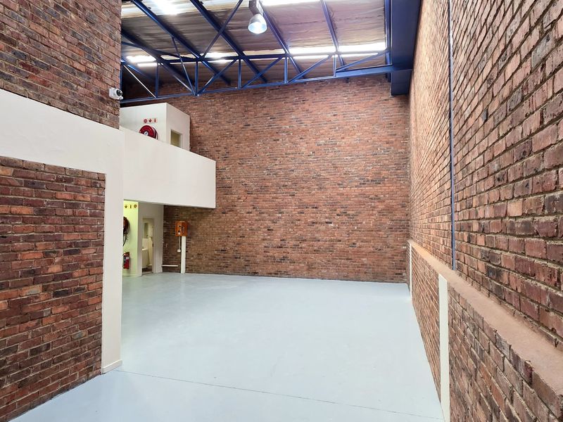 Spacious industrial utility area featuring high ceilings with exposed steel trusses, durable epoxy flooring, and classic face-brick walls with a mezzanine level.
