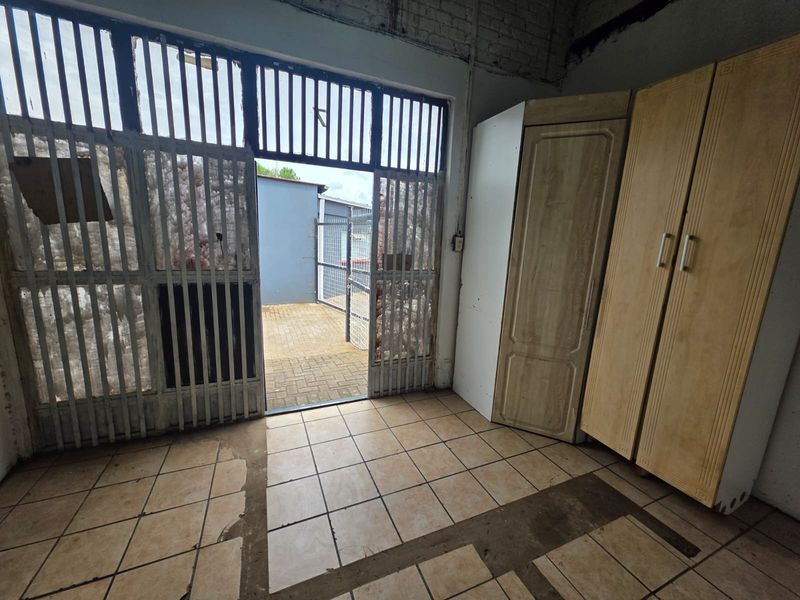 Interior utility space featuring tiled flooring and a metal security gate leading to an outdoor paved area.