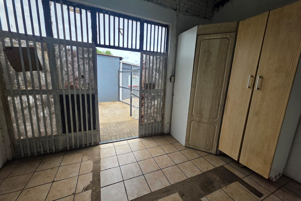 Interior utility space featuring tiled flooring and a metal security gate leading to an outdoor paved area.