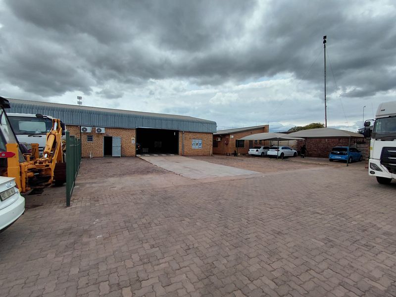 Industrial property featuring a large warehouse structure, paved yard area, and covered parking bays suitable for commercial or logistics operations.