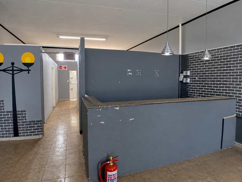 Commercial office space featuring a built-in reception counter, tiled flooring, and modern pendant lighting, suitable for a professional reception or service area.