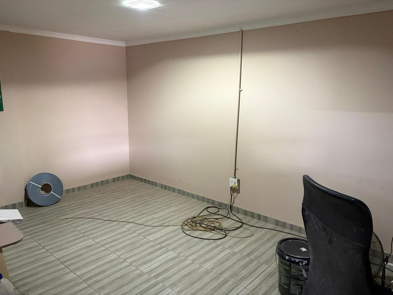 A functional, empty office space featuring tiled flooring and surface-mounted electrical infrastructure, suitable for a variety of industrial or commercial uses.