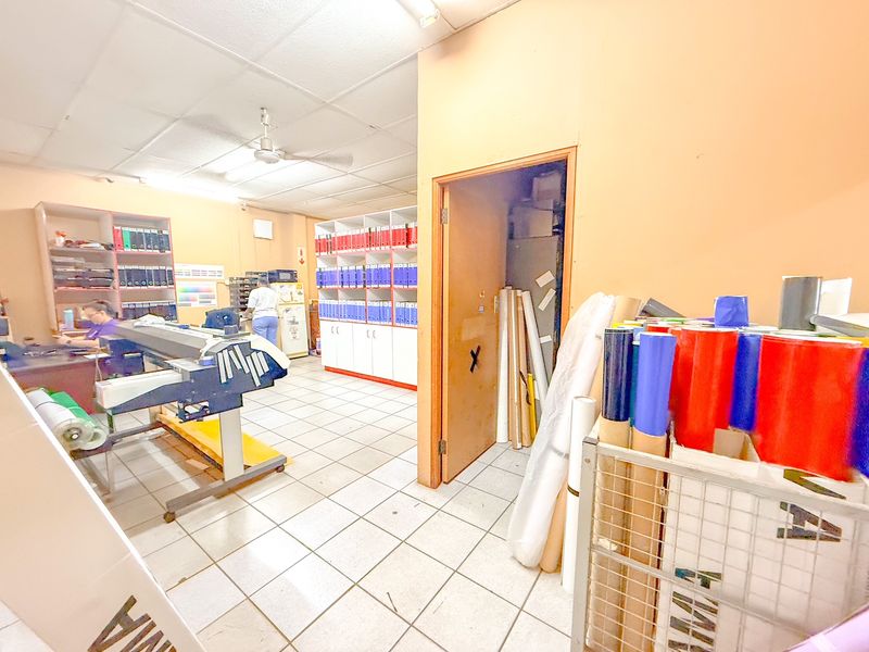 Industrial workspace featuring tiled flooring, built-in storage shelving, and a separate utility or storage room access.