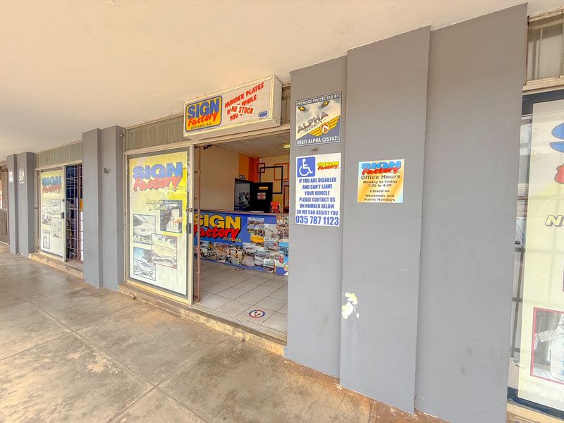 Commercial storefront entrance featuring a covered walkway, glass display windows, and signage, suitable for retail or office use.