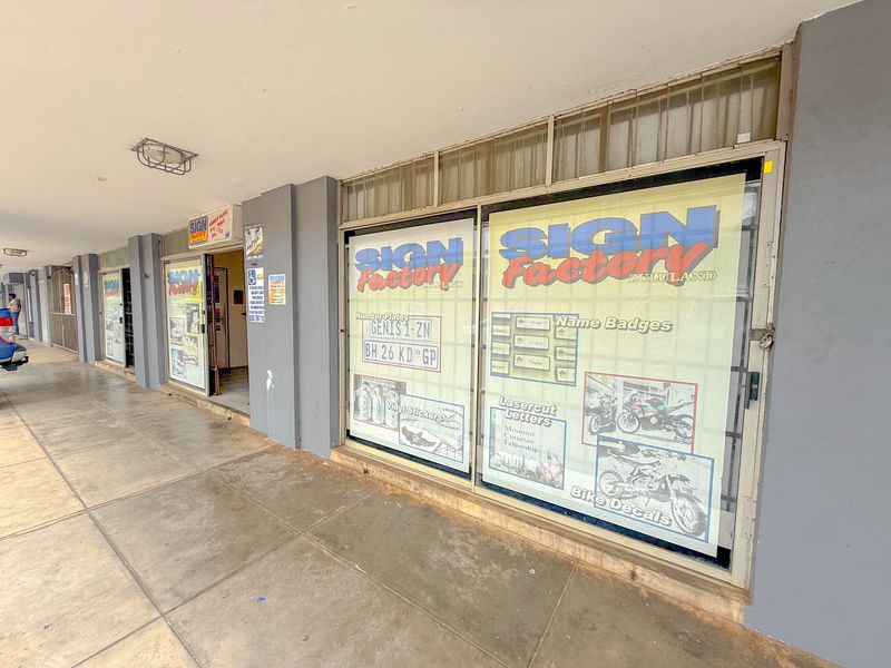Exterior view of a commercial industrial unit featuring large glass display windows and a covered walkway entrance.