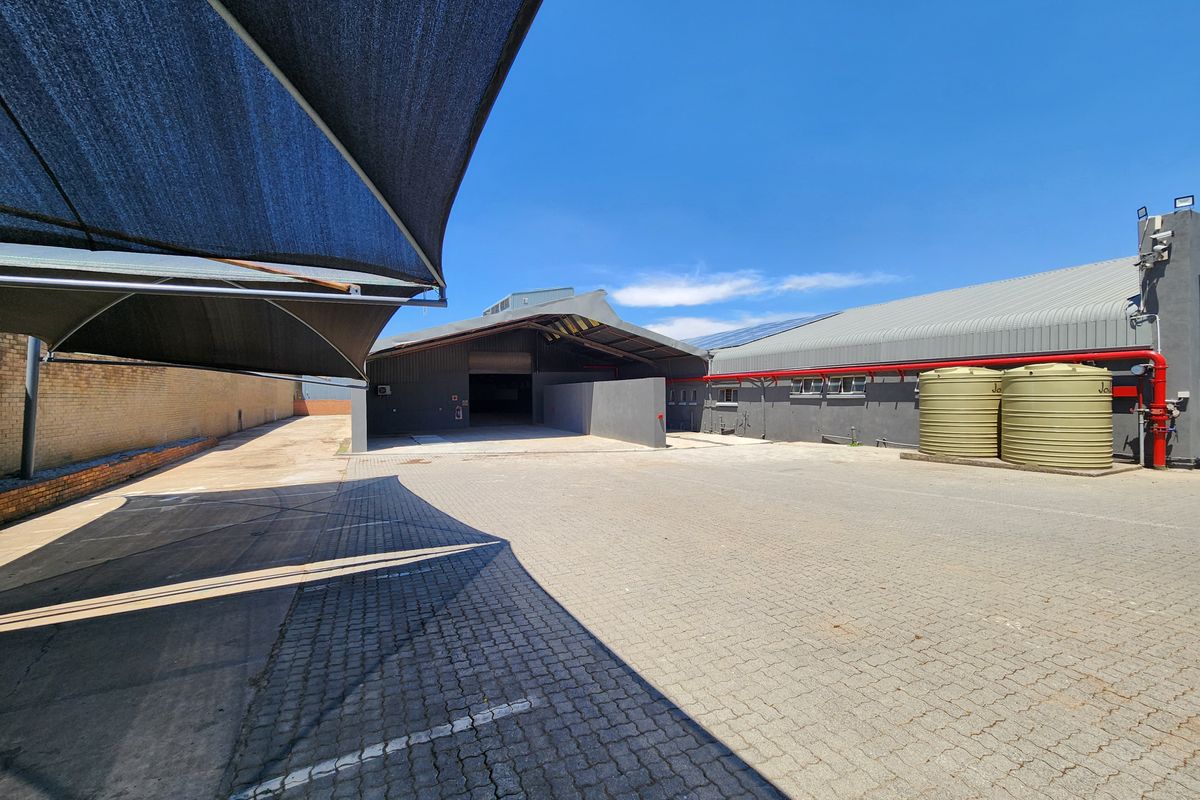 Spacious industrial rear yard featuring paved surfacing, shade sail parking, and external water storage tanks with integrated fire safety infrastructure.