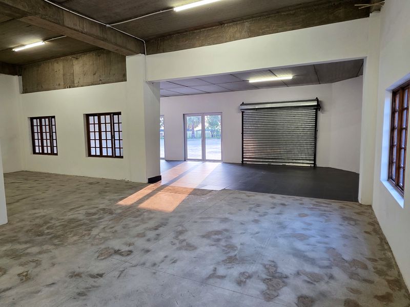 Spacious open-plan industrial unit featuring exposed concrete ceilings, durable concrete flooring, and a secure roller shutter door, ideal for versatile commercial or workshop use.