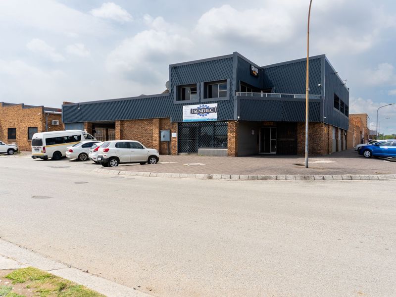 Front exterior view of a commercial building featuring a combination of brickwork and modern dark metal cladding with a balcony and security entrance.