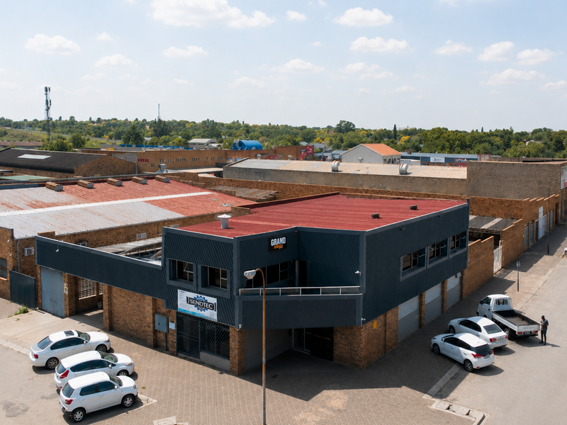 Aerial view of a commercial industrial property featuring face brick construction, metal cladding, and corrugated roofing with adjacent paved parking areas.