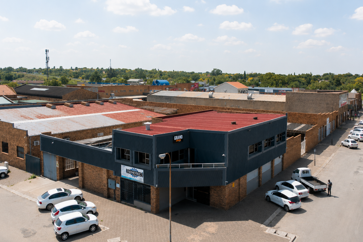 Aerial view of a commercial industrial property featuring face brick construction, metal cladding, and corrugated roofing with adjacent paved parking areas.