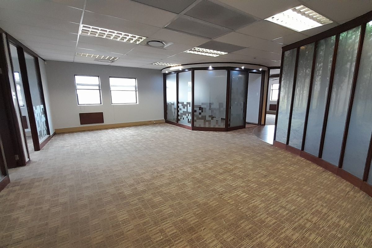 Spacious open-plan office area featuring suspended ceilings, recessed lighting, and modern frosted glass partitions, providing a versatile and professional workspace environment.