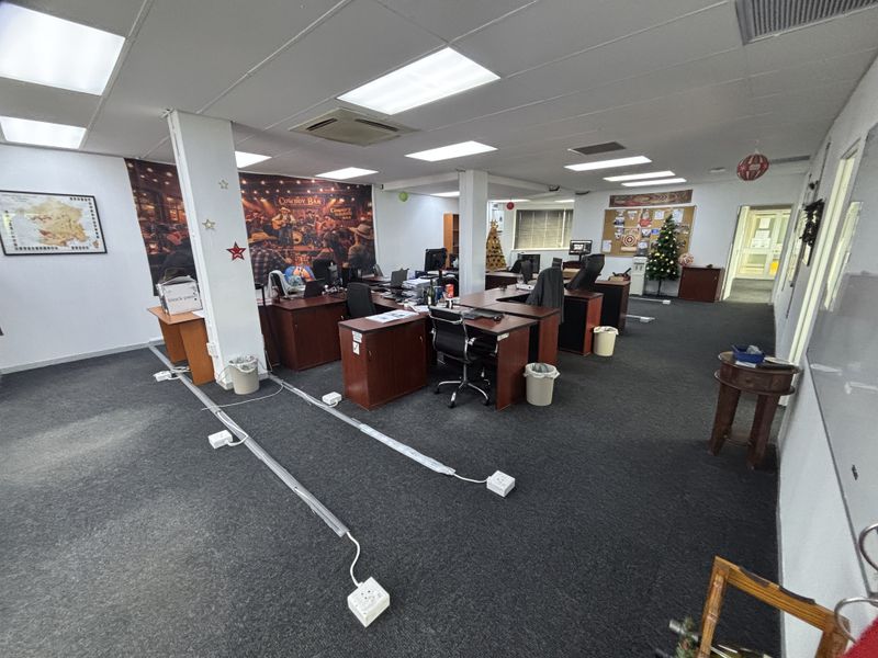 Open-plan office space featuring carpeted flooring, recessed ceiling lighting, and integrated air conditioning, currently configured with multiple workstations.