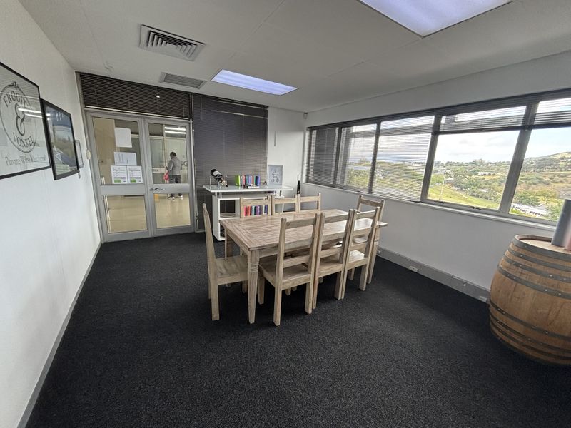 A functional office space featuring large windows with venetian blinds, recessed ceiling lighting, and carpeted flooring, offering a bright and professional work environment.