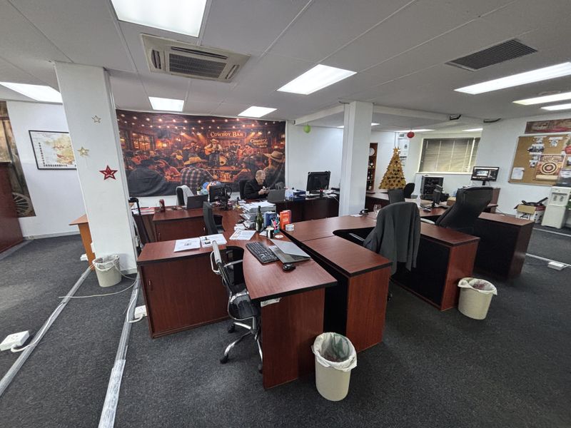 Open-plan office space featuring suspended ceilings, recessed lighting, integrated air conditioning, and carpeted flooring, providing a functional workspace environment.