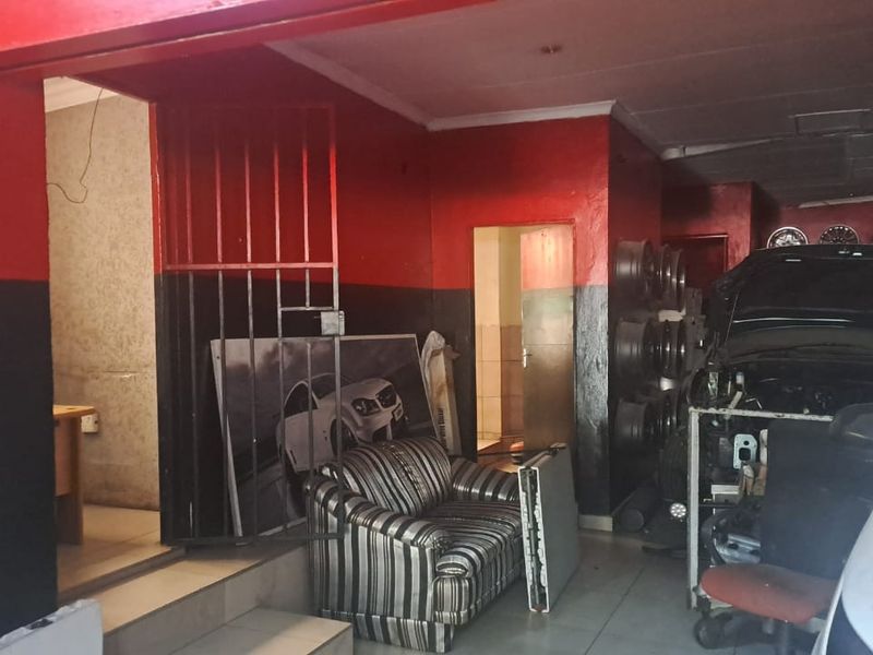 A functional workshop or retail space featuring tiled flooring, high-contrast wall paint, and integrated structural access points for automotive service or display.