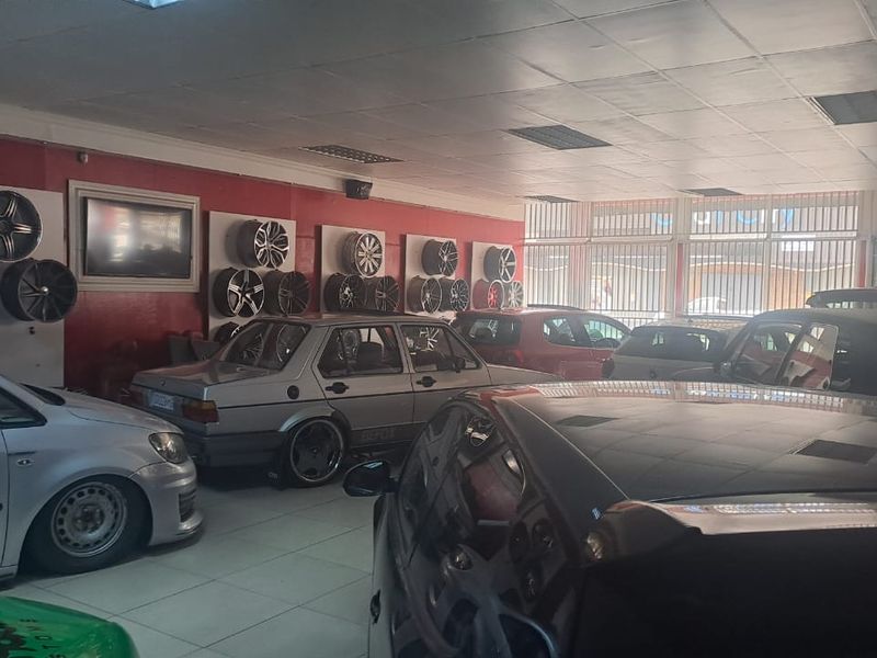 A retail showroom space featuring tiled flooring, recessed ceiling lighting, and wall-mounted display panels for automotive accessories.