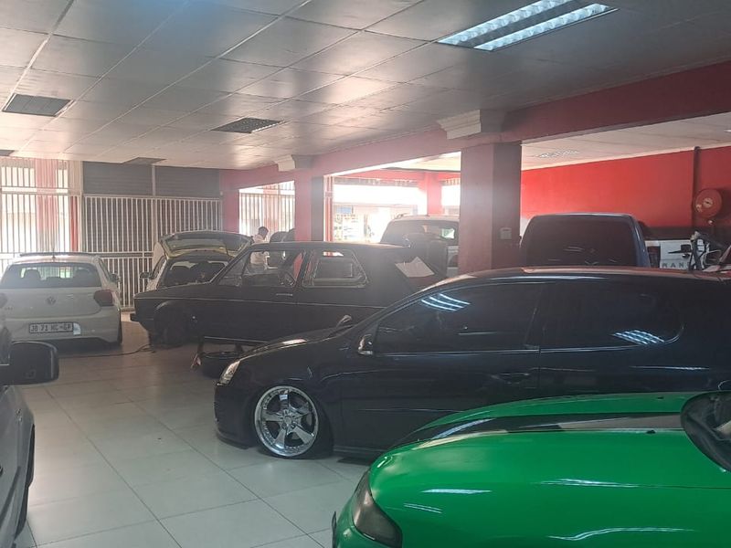 Spacious commercial garage or workshop area featuring tiled flooring, recessed ceiling lighting, and secure metal security gates.