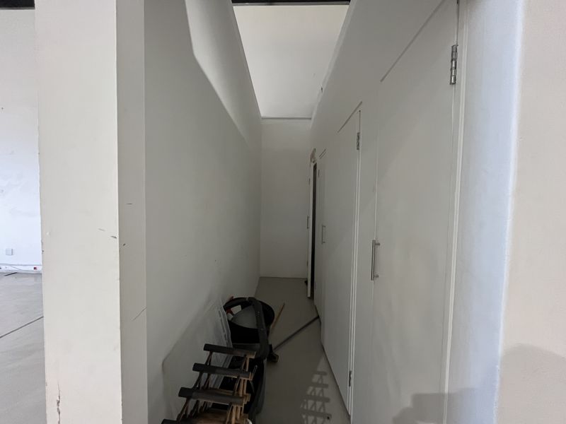A narrow hallway featuring multiple built-in storage cupboards with modern handles, providing functional utility space within the retail property.