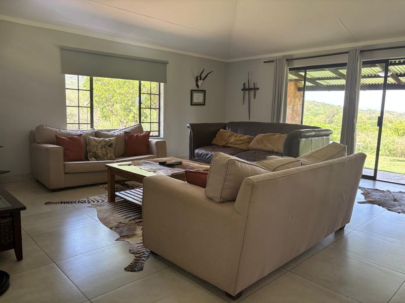 Spacious living room featuring large windows, tiled flooring, and sliding glass doors that provide natural light and access to the outdoor area.