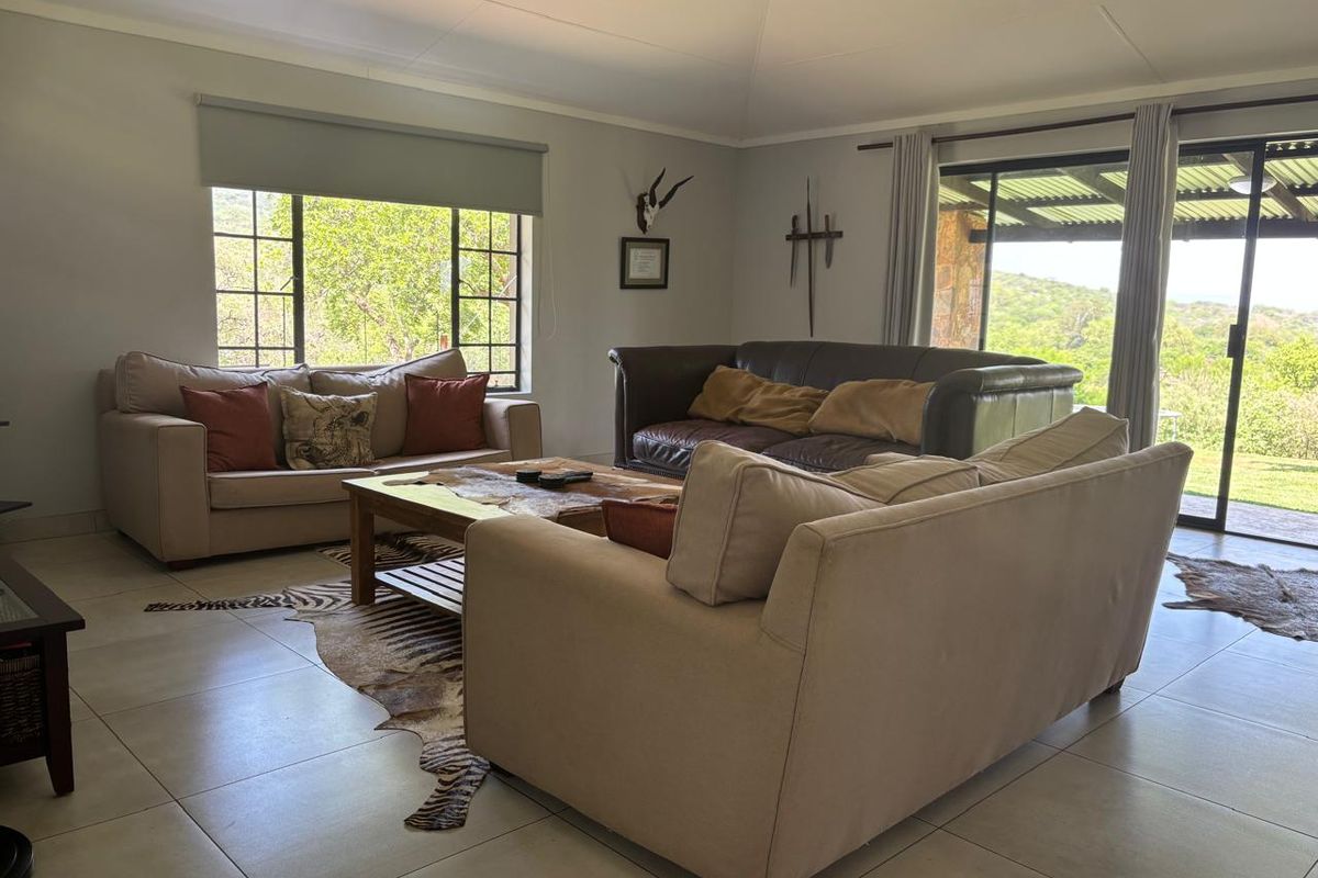 Spacious living room featuring large windows, tiled flooring, and sliding glass doors that provide natural light and access to the outdoor area.