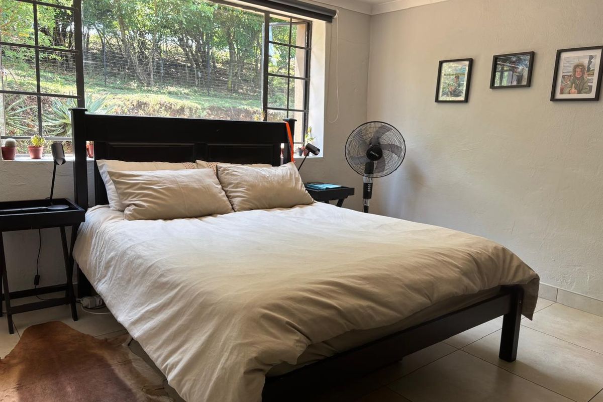 A bedroom featuring tiled flooring and a large window providing natural light and garden views.