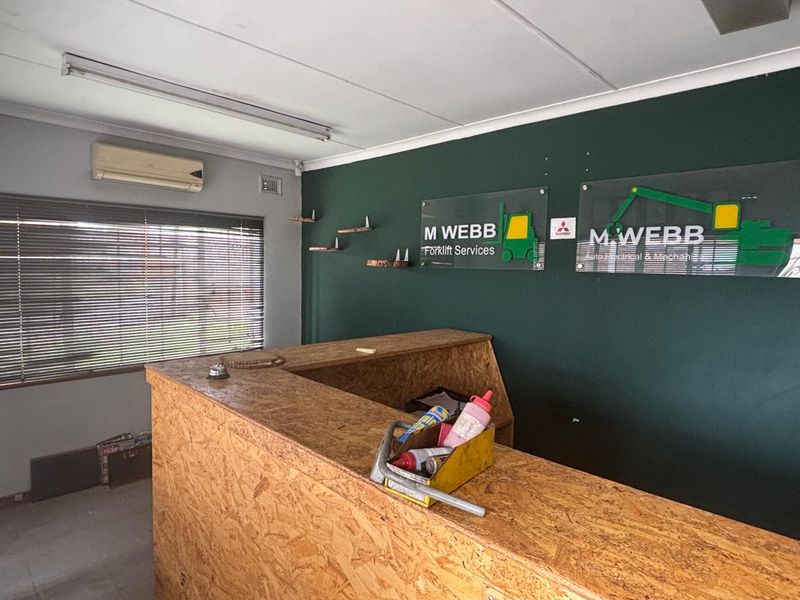 Industrial reception area featuring a built-in counter, split-system air conditioning, and functional lighting, suitable for a professional service office environment.